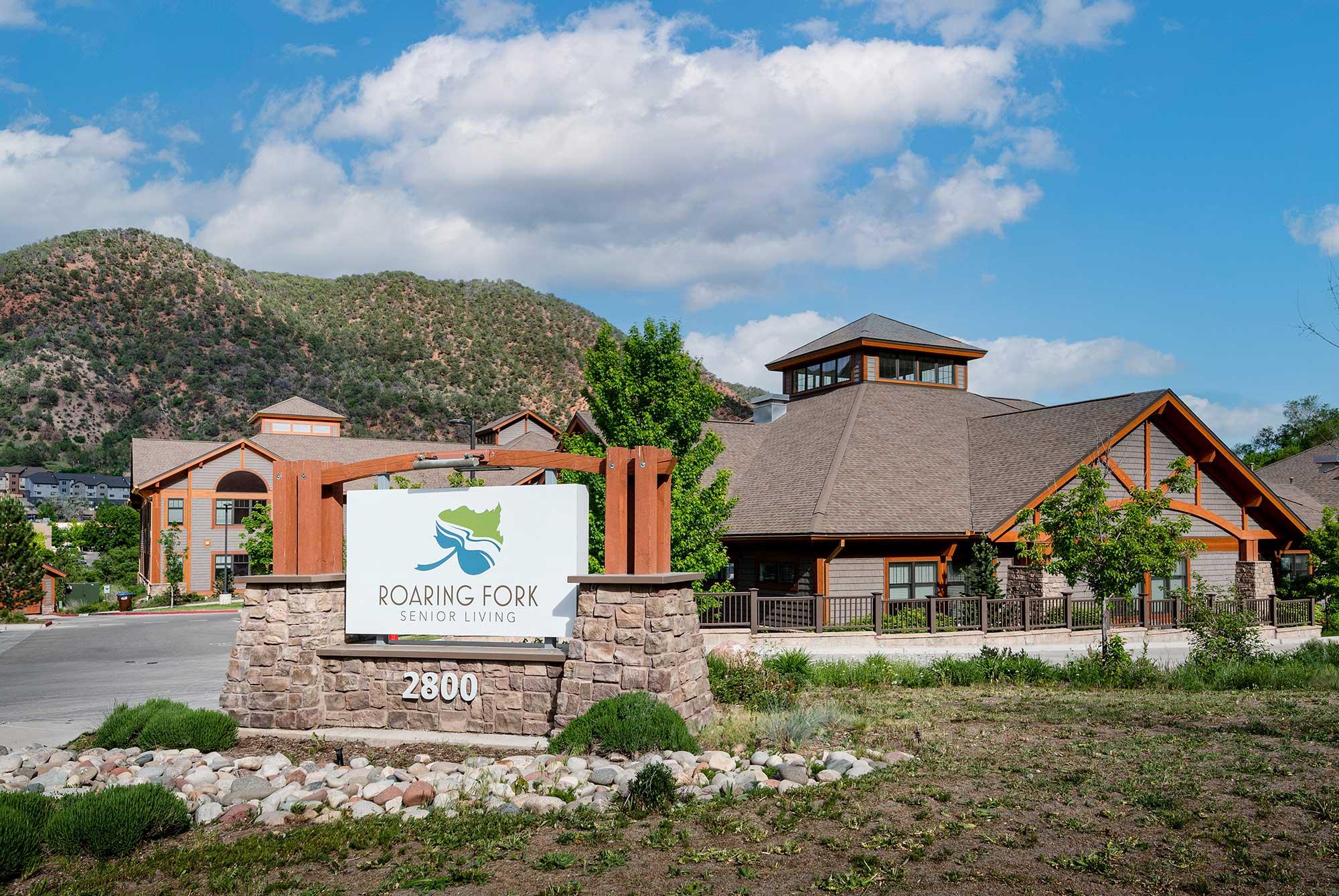 The front entrance and main signage of Roaring Fork Senior Living, showcasing the scenic surrounding area.